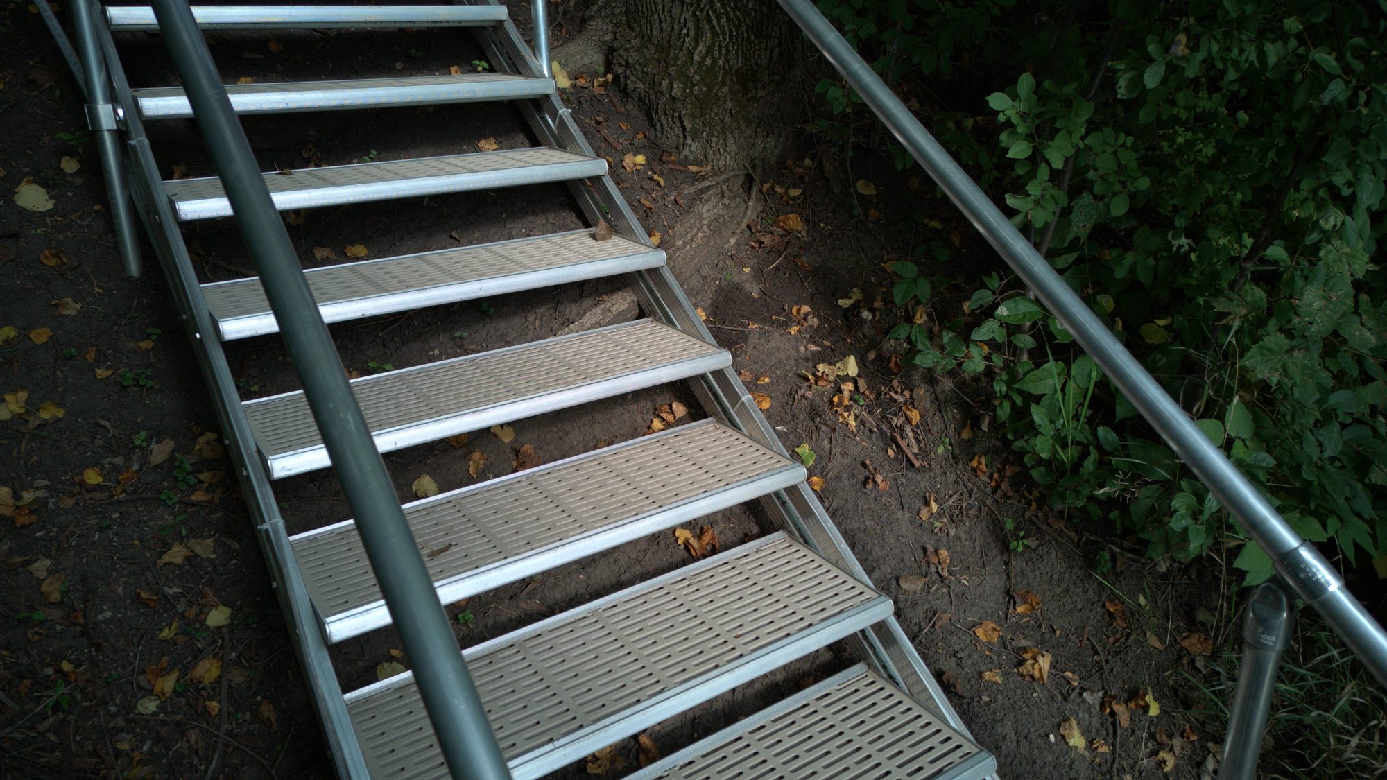 Aluminum stairway with perforated treads on a shaded slope