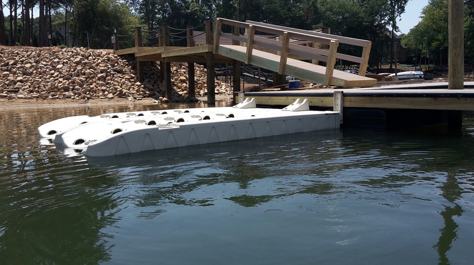 White floating drive-on dock beside a wooden gangway ramp