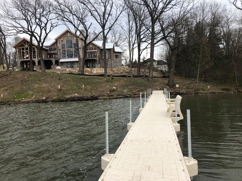 Paver-texture floating dock walkway to a timber-frame lakehouse